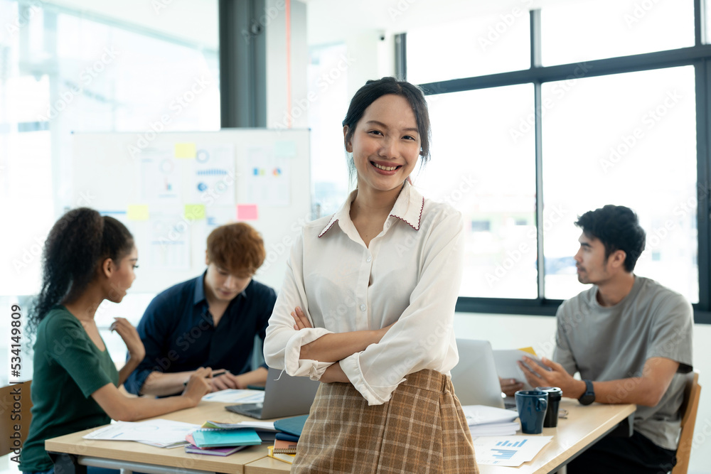 Attractive young asian woman standing confident in the office in front of her team in meeting room.