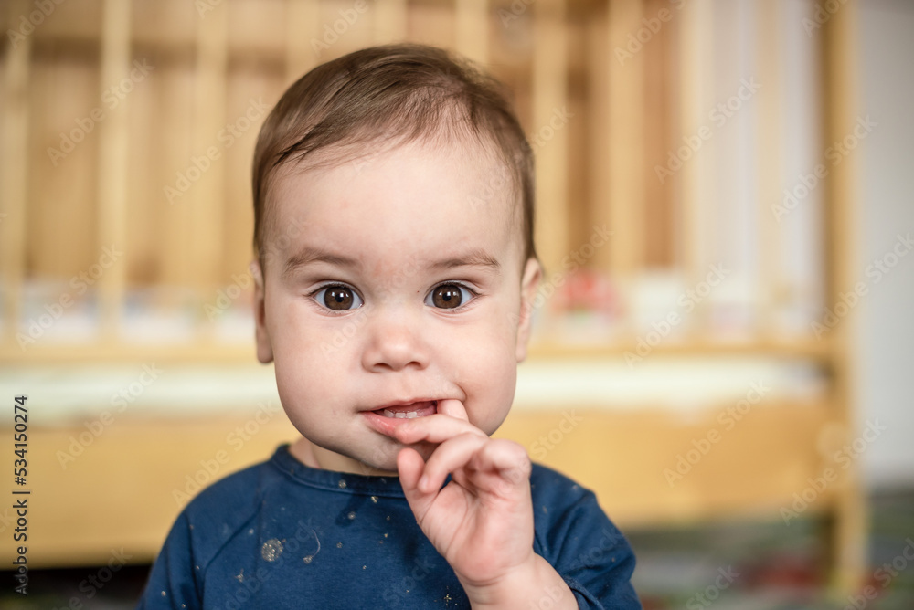 a little girl holds her fingers in her mouth