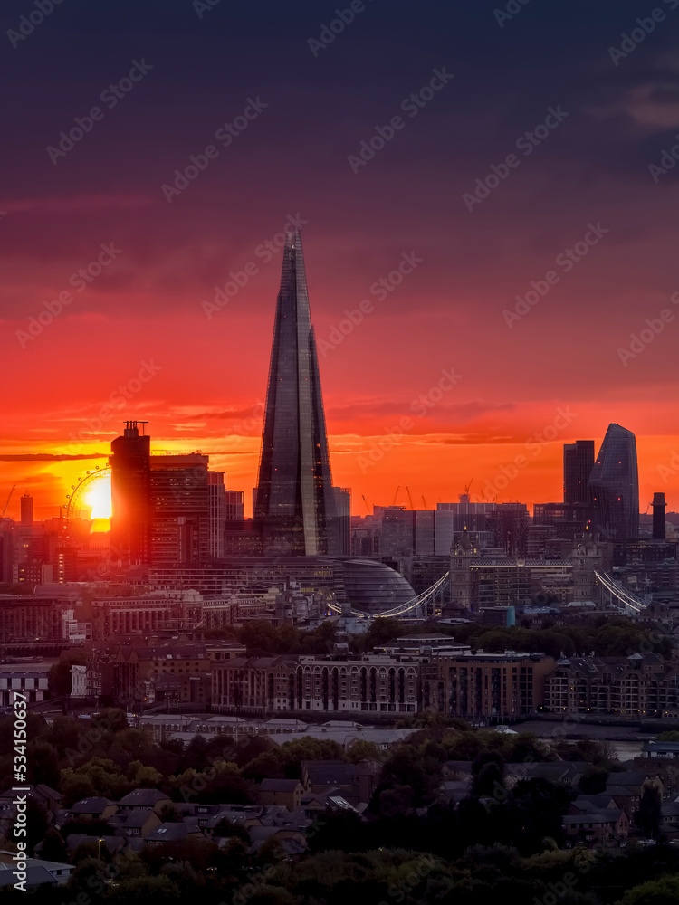 Elevated view of the London skyline during a cloudy sunset with intense red colors and sunlight during autmn time, England