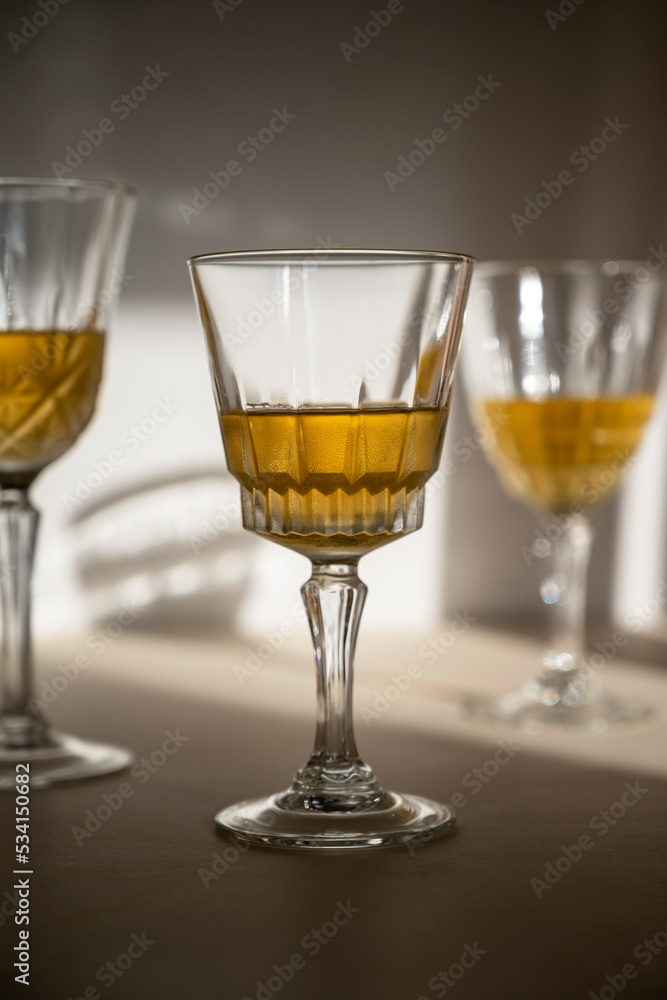 Alcohol drink in crystal glasses, sun light, shadows. Brandy or whiskey drink creative natural light.