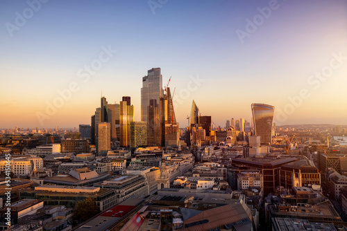 The urban skyline of the City of London during a golden sunset with the completed office skyscrapers reflecting the soft sunlight