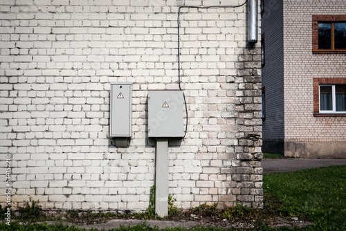 Electrical distribution boxes against a white brick wall