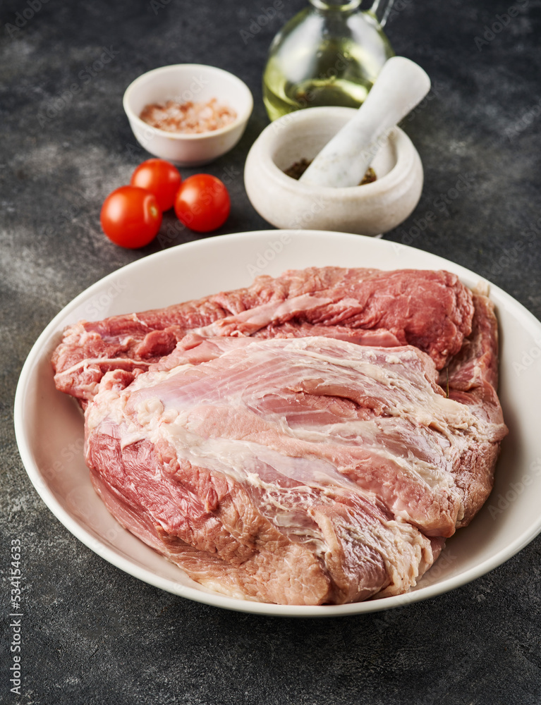 Fresh raw pork shoulder with ingredients for marinade: pepper, salt, olive oil, rosemary, garlic, view from above, close-up Fresh raw pork shoulder with ingredients for marinade: pepper, salt, olive oil, rosemary, garlic, view from above, close-up