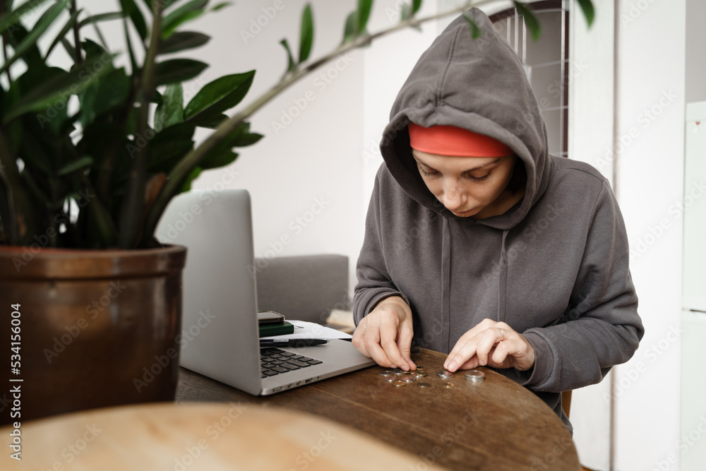 Woman with hat in cold winter home counting coins. Energy crisis and inflation Woman with hat in cold winter home counting coins. Energy crisis and inflation