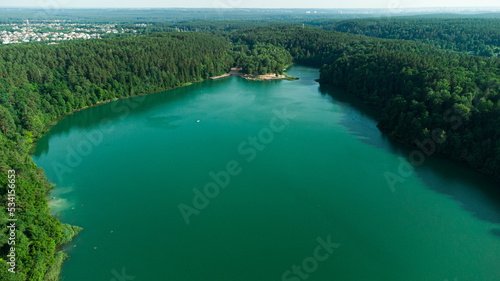 Green lake around forest. Aerial drone view