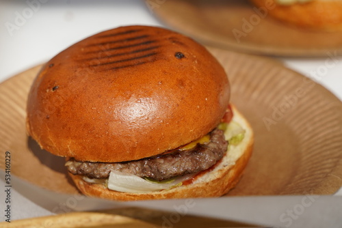 Freshly baked burger on a cardboard plate.