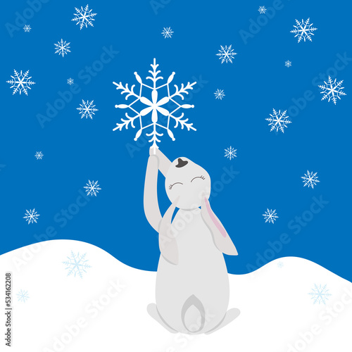 White hare or rabbit catches a falling snowflake in the snow. Holiday card, symbol of 2023
