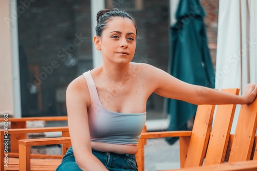 Young girl sitting on the bench with her hand outstretched photo