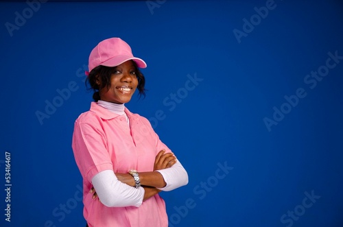 Young girl in pink outfit standing with crossed hands against blue background photo