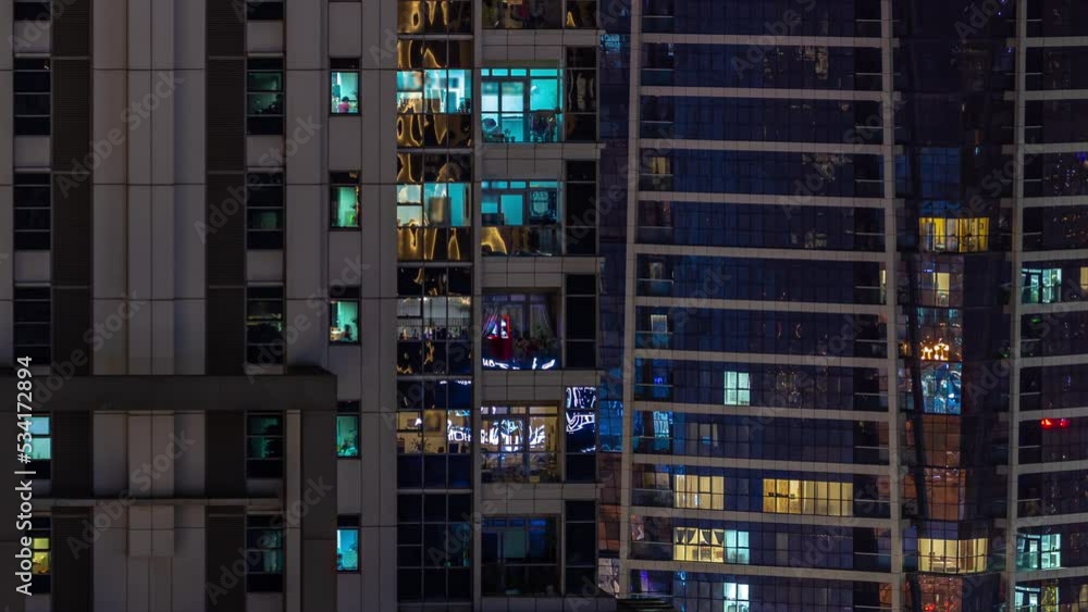 Apartment windows of a glazed skyscraper glow at night with city lights reflection aerial timelapse. Illuminated towers in downtown district Apartment windows of a glazed skyscraper glow at night with city lights reflection aerial timelapse. Illuminated towers in downtown district