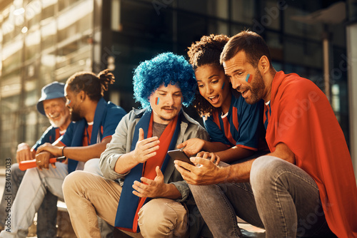 Group of sports fans watching soccer match via live stream on cell phone.