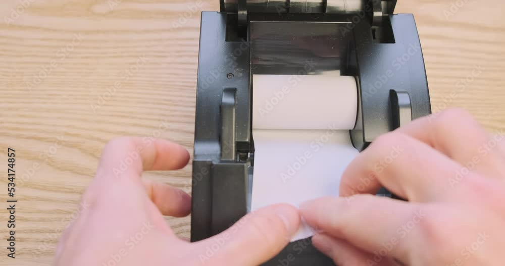 Replacing the thermal paper roll in a receipt printer. First person