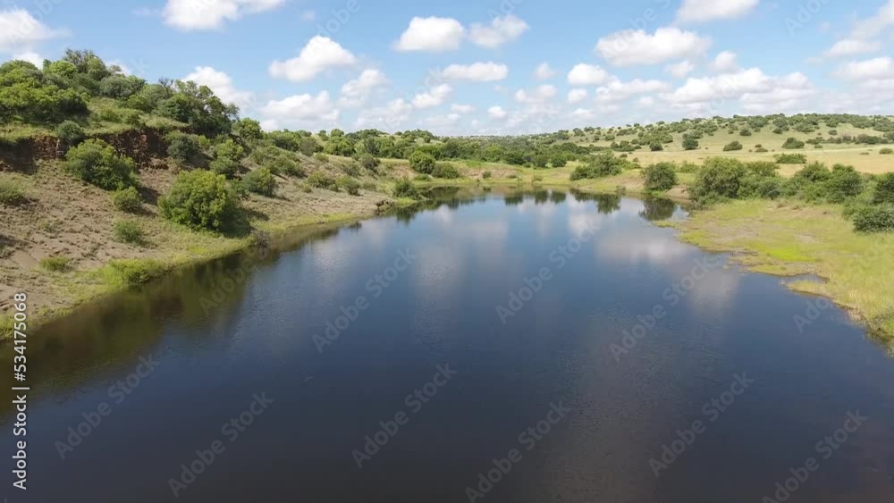 Beautiful pond reflecting the sky surrounded by lush green grass field Beautiful pond reflecting the sky surrounded by lush green grass field