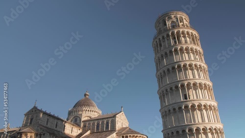 still shot with one bird crossing to the right in front of the leaning tower of pisa in tuscany italy during the morning and golden hour photo