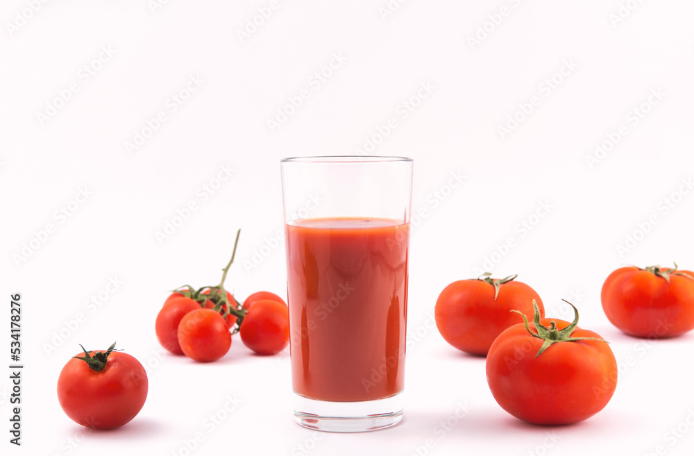 Tomato juice in a glass and ripe tomatoes on a white background Tomato juice in a glass and ripe tomatoes on a white background