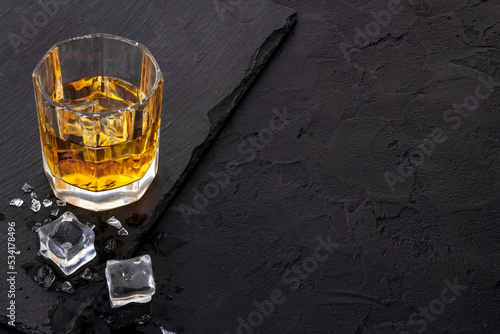 Glass of golden whiskey with ice. Strong alcoholic drink background