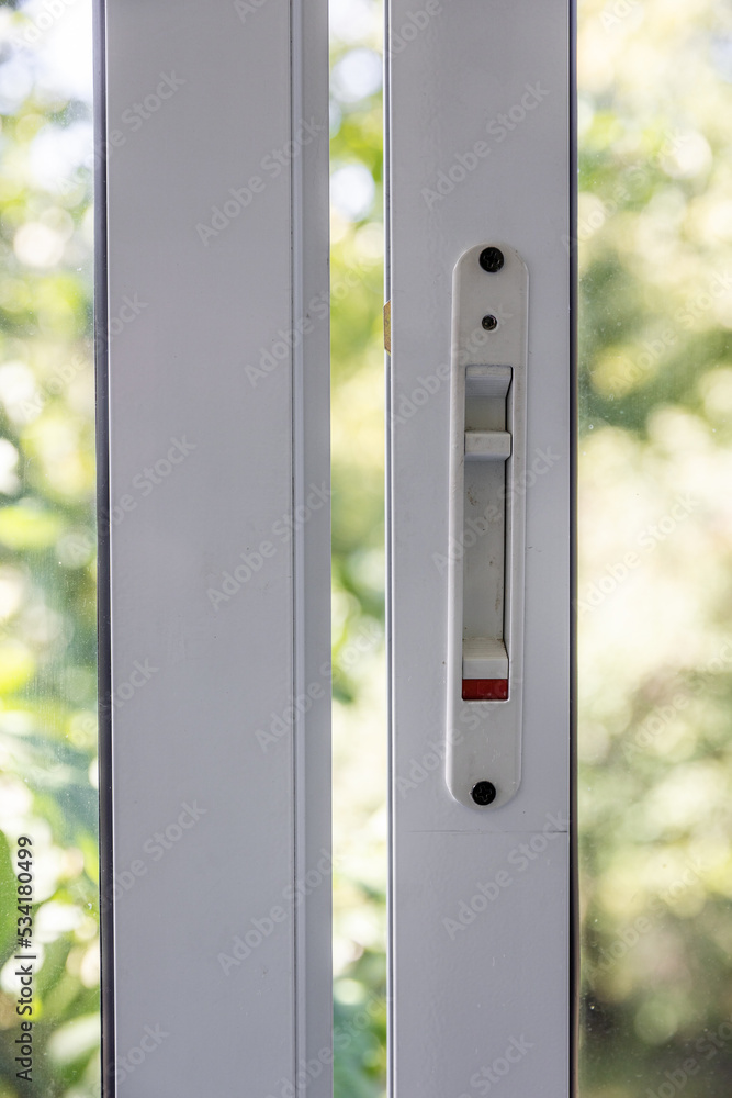 Close-up of a double-glazed balcony frame with a latch and fastening for safe ventilation. Single-sided window handle. House door and window repair concept Close-up of a double-glazed balcony frame with a latch and fastening for safe ventilation. Single-sided window handle. House door and window repair concept