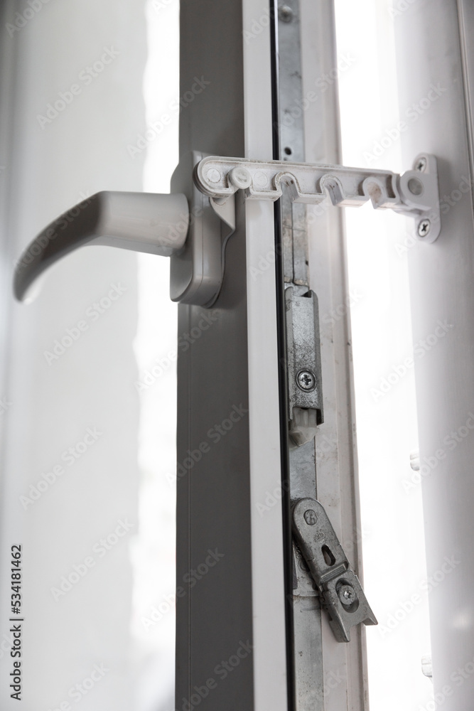 Close-up shot of a double-glazed plastic door frame, one-way balcony window handle,PVC window latch fixes the sash.House door and window repair concept Close-up shot of a double-glazed plastic door frame, one-way balcony window handle,PVC window latch fixes the sash.House door and window repair concept