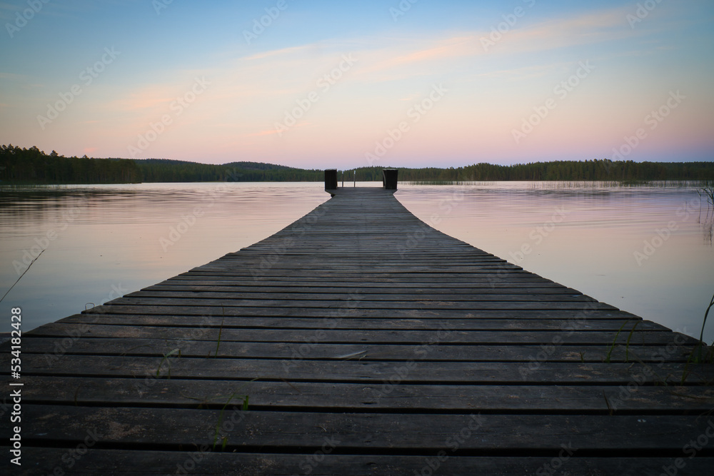 Fototapeta premium Wooden jetty reaching into a swedish lake at blue hour. Nature from Scandinavia