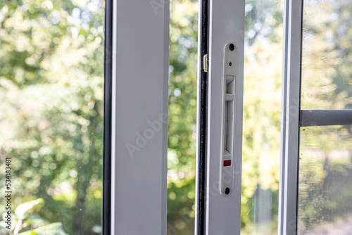 Close-up of a double-glazed balcony frame with a latch and fastening for safe ventilation. Single-sided window handle. House door and window repair concept