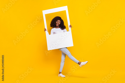 Full size photo of excited carefree girl hold paper album card good mood isolated on yellow color background