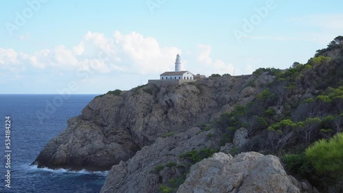 he lighthouse of Cala Ratjada. Waves splashing on a rocky coastline of Mallorca in the mediterranean sea. Deep blue water and steep cliffs. 4k. 