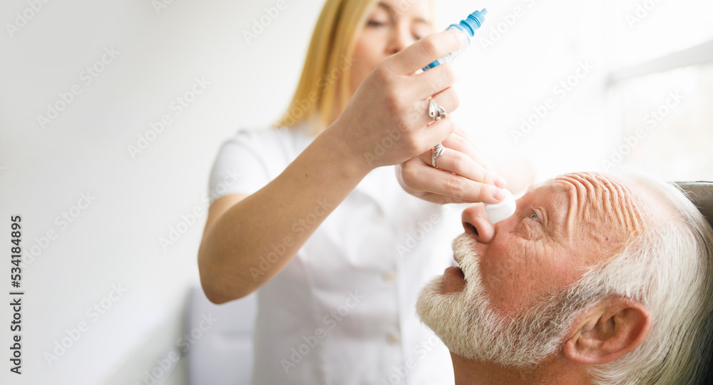 Female doctor giving eye drops to his elderly patient Female doctor giving eye drops to his elderly patient