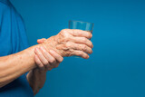 Close-up of hands senior woman trying to hold a glass of water