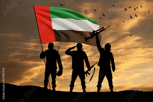 Silhouettes of soldiers with the flag of UAE on background of the sunset or the sunrise. Commemoration Day. photo