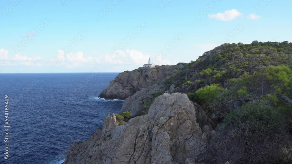 he lighthouse of Cala Ratjada. Waves splashing on a rocky coastline of Mallorca in the mediterranean sea. Deep blue water and steep cliffs. 4k. he lighthouse of Cala Ratjada. Waves splashing on a rocky coastline of Mallorca in the mediterranean sea. Deep blue water and steep cliffs. 4k.