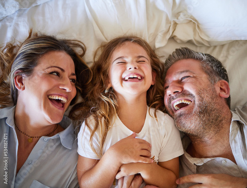 Mother, father and child happy in bed together in the morning, laughing at joke and bonding in house. Family with love in home bedroom, being funny and smile for comedy while relax with girl