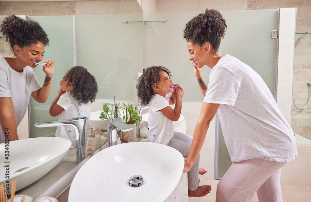 Child, dental and toothbrush with a girl and her mother brushing their teeth together in the bathroom of their home. Family, hygiene and oral with a woman and daughter practicing care and hygiene Child, dental and toothbrush with a girl and her mother brushing their teeth together in the bathroom of their home. Family, hygiene and oral with a woman and daughter practicing care and hygiene