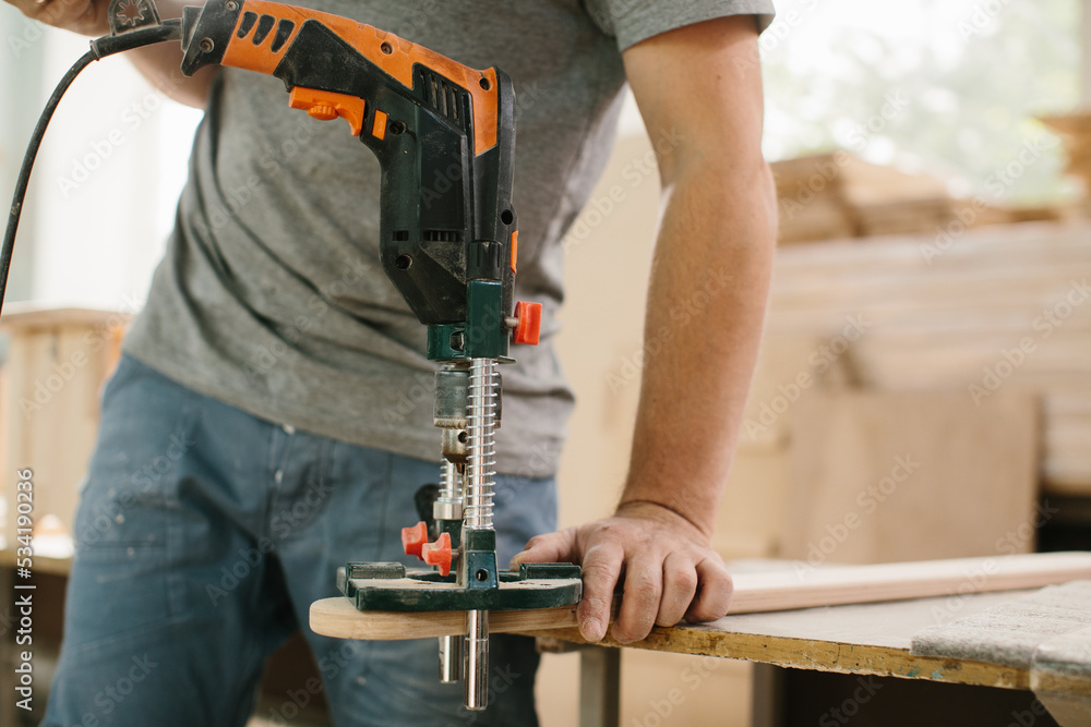 The master works in a studio and drill a hole in a wooden board. The master works in a studio and drill a hole in a wooden board.