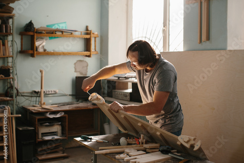 An adult, male carpenter working with tools in his wood shop - stock photo