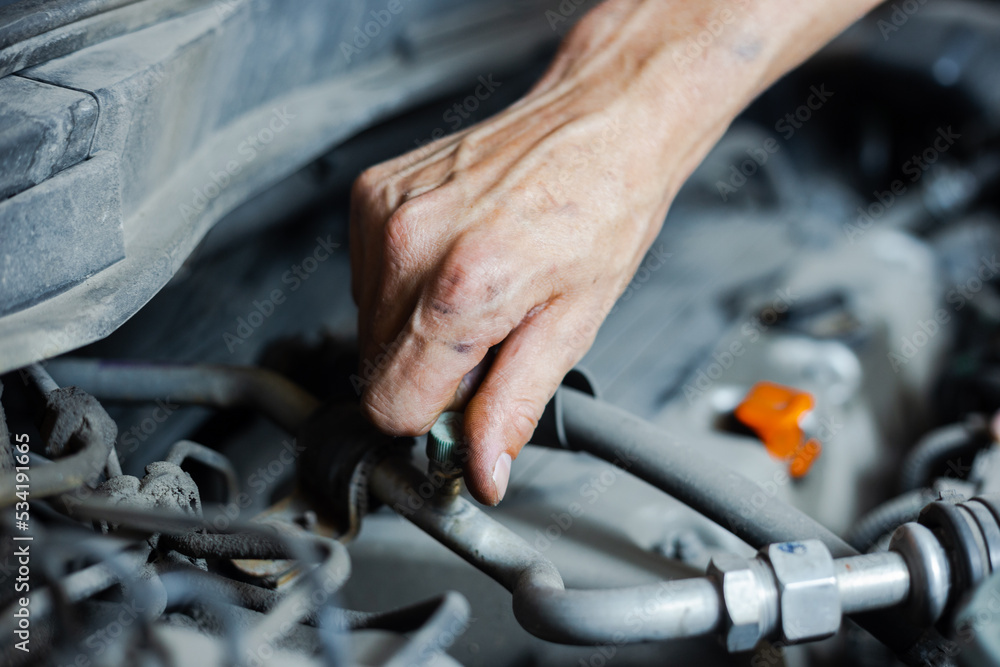Obraz premium An auto mechanic works with a car engine in the mechanics' garage. Car repair close-up. An authentic close-up shot of an auto mechanic's hands.