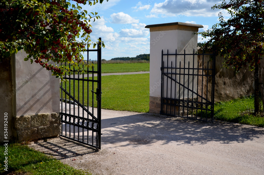 gate and fence at the castle in the autumn sun. the lattice ending the end of wall protected thieves from improper intruders. spike shaped with stop and door hinges, pillar, square, plaster gate and fence at the castle in the autumn sun. the lattice ending the end of wall protected thieves from improper intruders. spike shaped with stop and door hinges, pillar, square, plaster