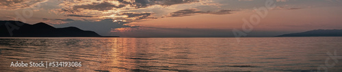 Colorful summer sunset on lake. Scenic dramatic clouds on sky.