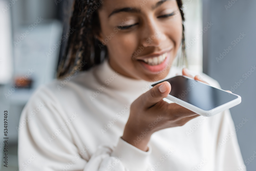 Blurred african american businesswoman recording voice message in office. Blurred african american businesswoman recording voice message in office.