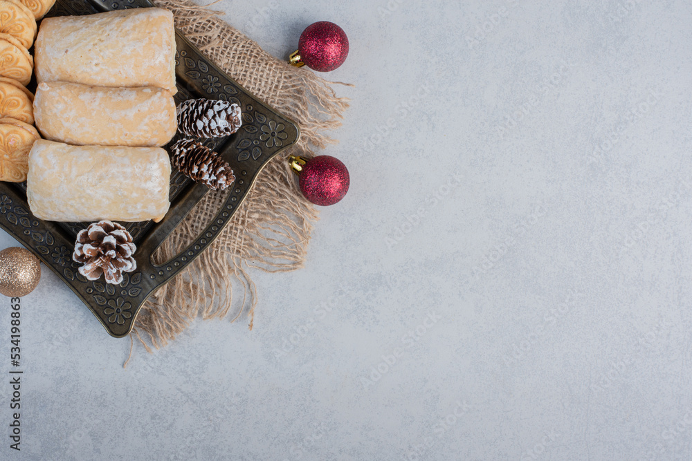 Assorted cookies on an ornate tray next to christmas baubles on marble background Assorted cookies on an ornate tray next to christmas baubles on marble background