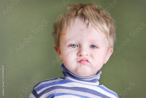 Disgruntled, angry child. A naughty difficult boy expresses dislike, frowns displeasedly. Copy space - concept of upset baby, neglect, disgust, childish irritability, bad behavior, negative feelings