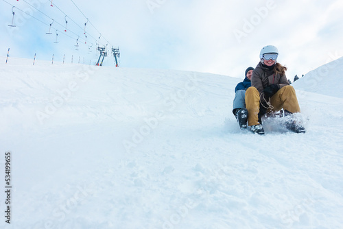 Crazy happy friends having fun with sledding on snow high mountains - Winter lifestyle concept