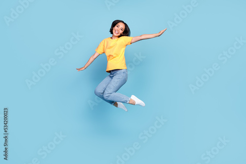Full length portrait of excited crazy person jumping arms wings flying isolated on blue color background