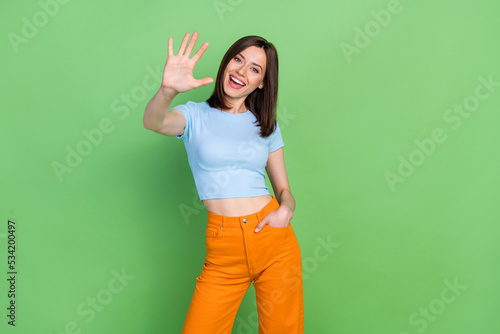 Photo of cheerful nice person toothy smile arm palm waving hi give high five isolated on green color background