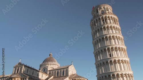 Still shot of leaning tower of pisa in tuscany with three birds flying to the left, golden hour, morning clear blue sky photo