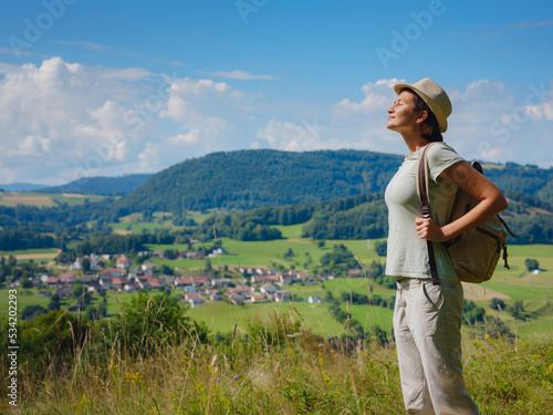 travel to summer Europe young asian woman. observation point above the village of Roggenburg, Switzerland. hike in summer forest, having a break