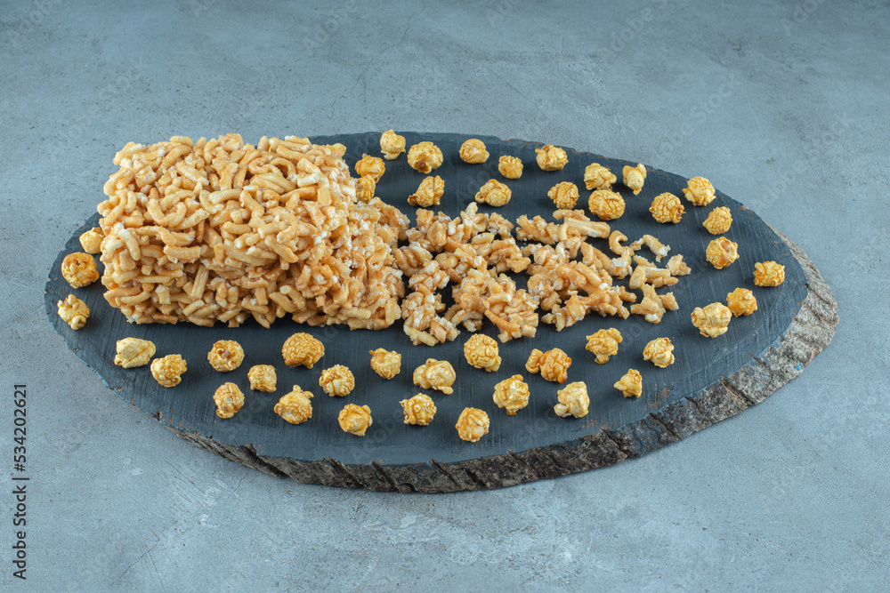 Caramel coated cake and a bunch of caramel popcorns on a board on marble background Caramel coated cake and a bunch of caramel popcorns on a board on marble background