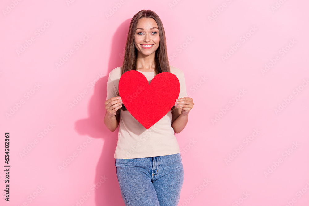 Portrait of gorgeous cheerful girl arms hold big paper heart card isolated on pink color background Portrait of gorgeous cheerful girl arms hold big paper heart card isolated on pink color background