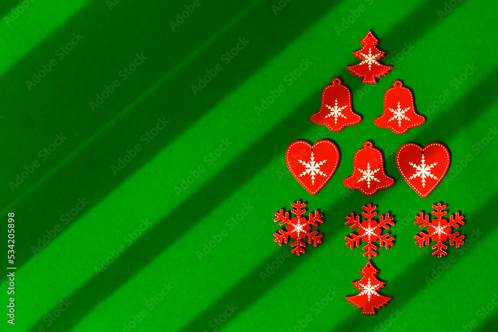 Red Christmas tree made of wooden Christmas tree toys on a green background with diagonal lines