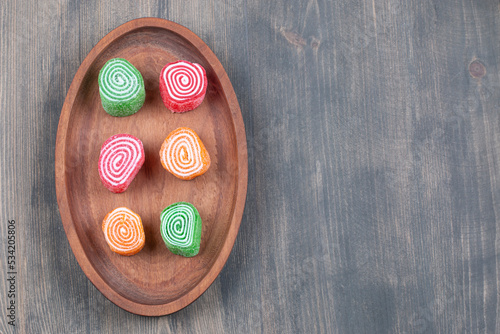 Colorful marmalade candies on wooden plate