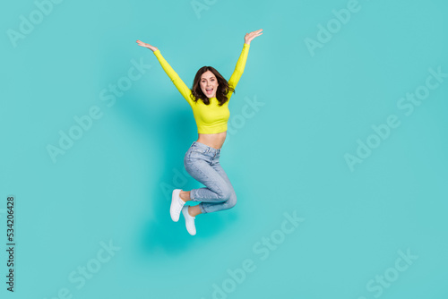 Full length portrait of satisfied cheerful young person jumping raise hands isolated on aquamarine color background